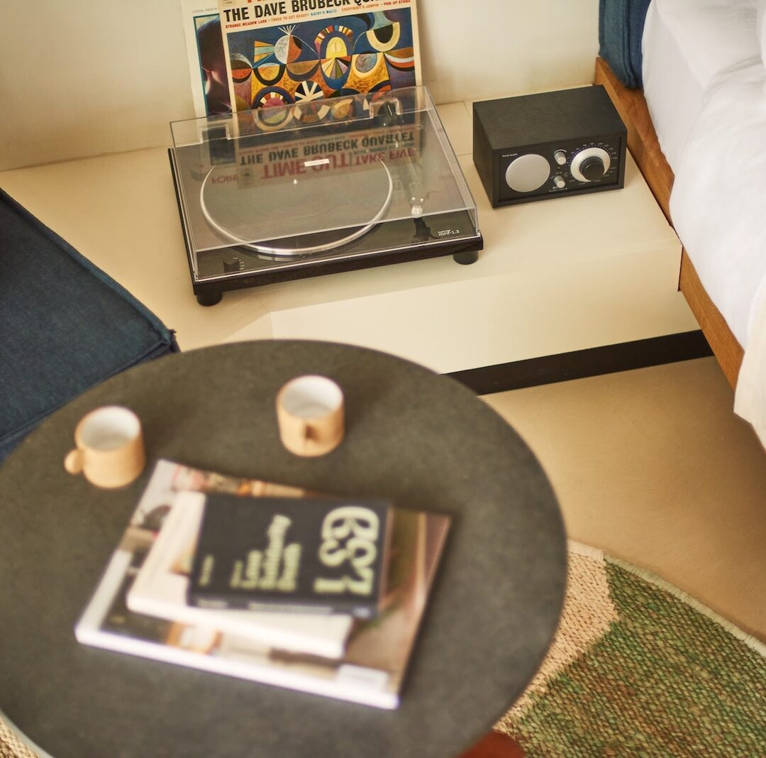 A small table featuring a vintage record player and a magazine, creating a cozy reading and listening space.