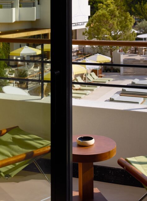 A scenic view of a sparkling pool seen from a cozy balcony, surrounded by lush greenery.