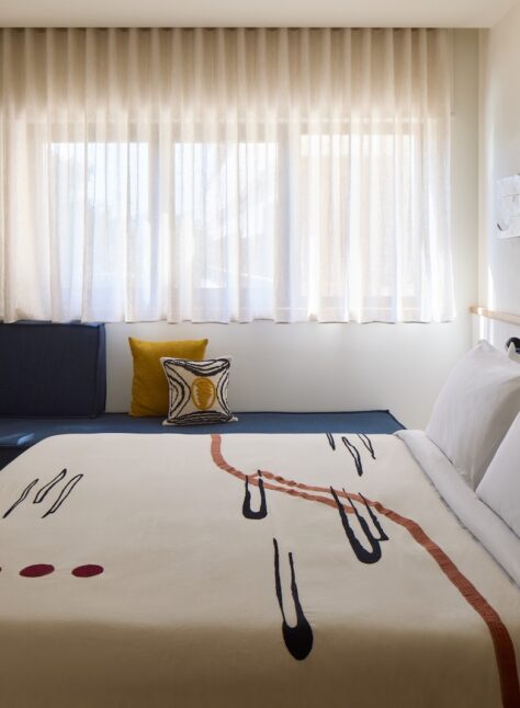 A stylish hotel room showcasing a bed, a television, and a window with sunlight streaming in