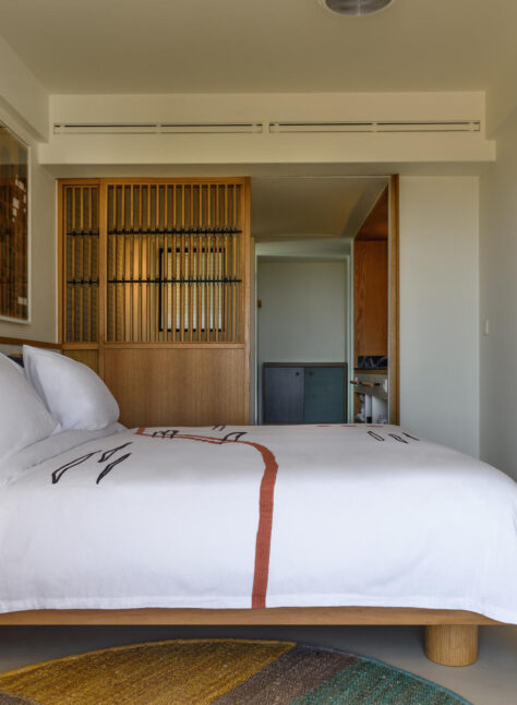 A cozy bed neatly made in a softly lit bedroom, with warm colors and simple decor.