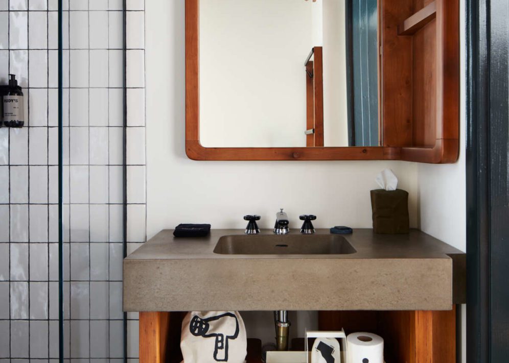 Sleek, modern bathroom with a concrete sink, walk-in shower and a wood detailed mirror