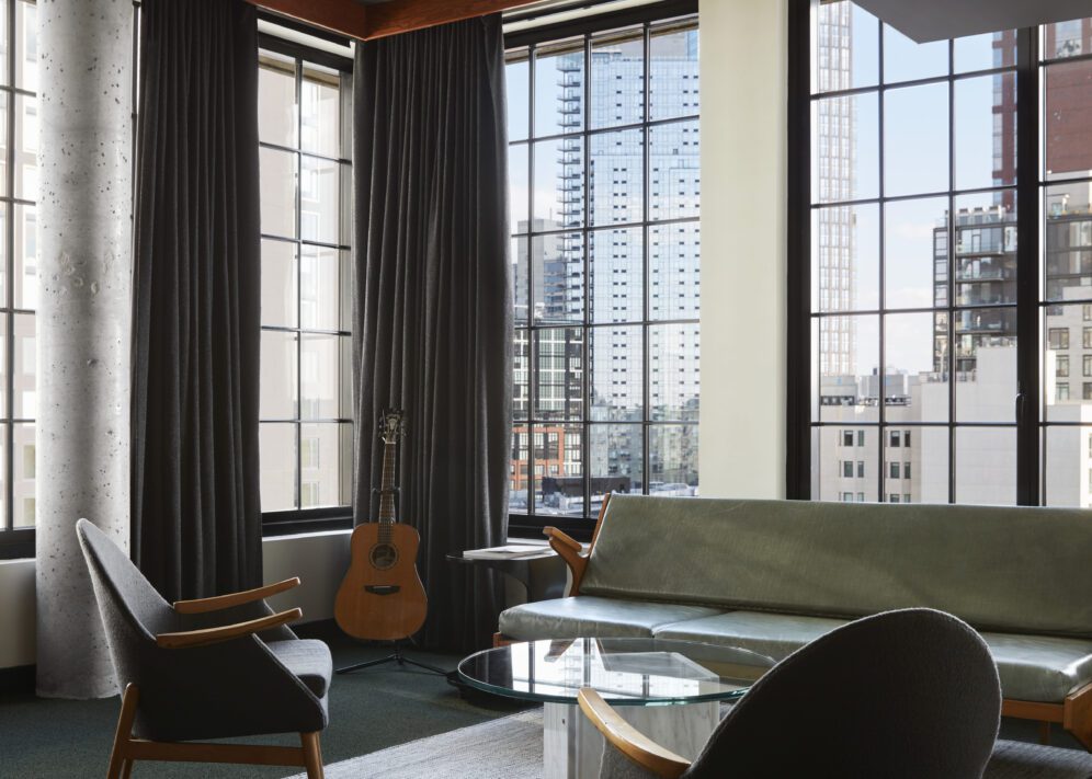 A living area featuring a modern concrete column and corner windows providing city views from multiple angles