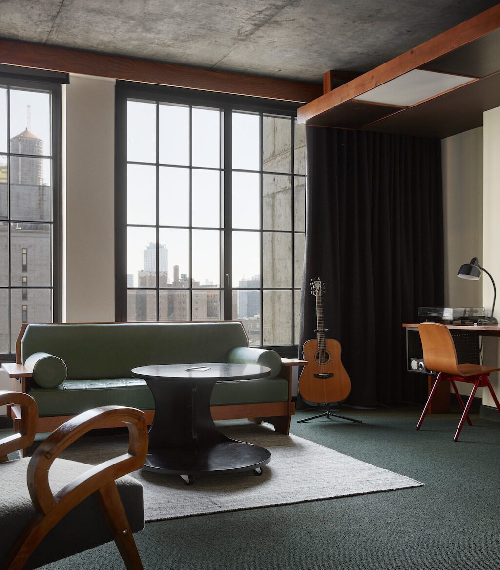 A high-floored room with a desk for work, multiple seating options and natural light