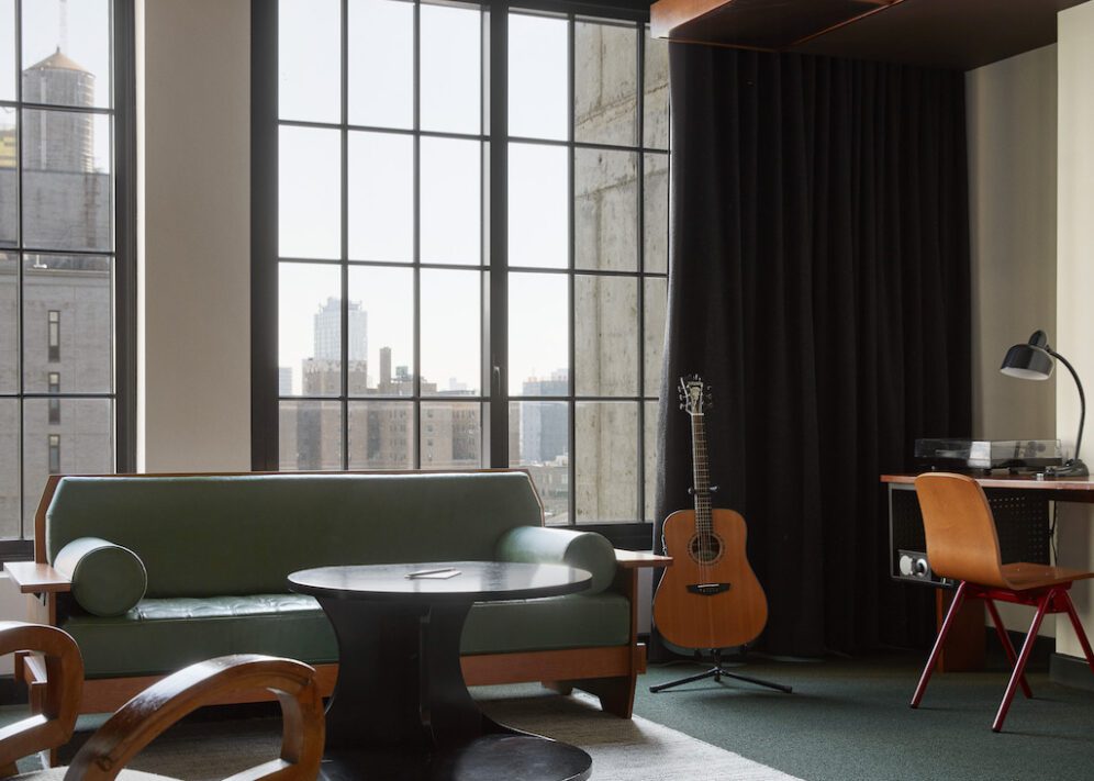 A high-floored room with a desk for work, multiple seating options and natural light