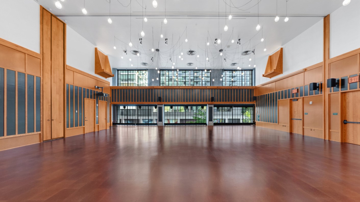 A spacious venue with suspended lights and dark wooden floors overlooks a city street