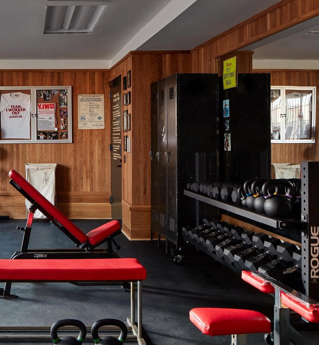 a photo of a gym with equipment that includes kettlebells, free weights and an exercise bench.