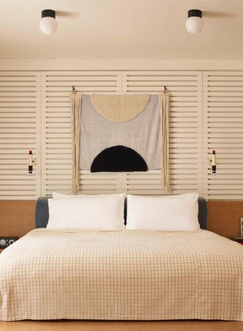 A private bedroom features a white, plaid bed flanked by a record player on one side and a radio and phone on the other