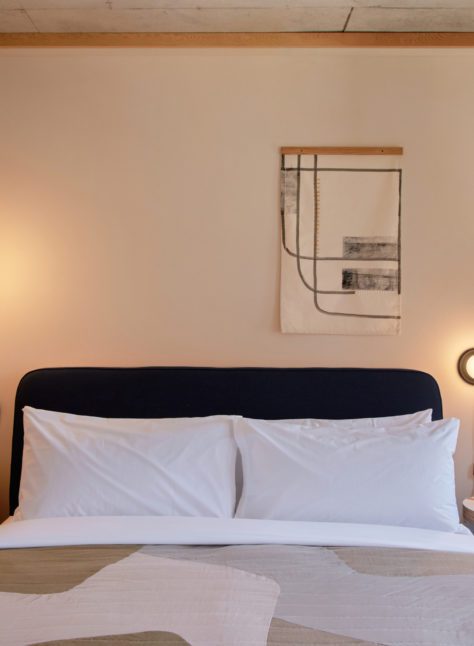 A bed sits in between two modern lights, providing a sense of ambience and calm
